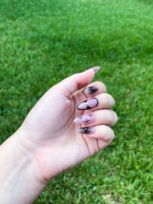 Starry Night Almond press-on nails with deep black and sparkling star accents in an elegant almond shape