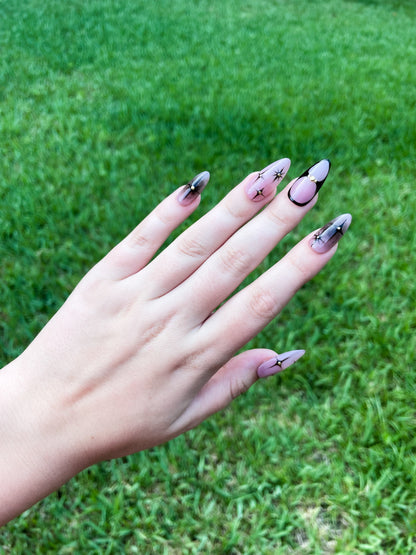 Starry Night Almond press-on nails with deep black and sparkling star accents in an elegant almond shape